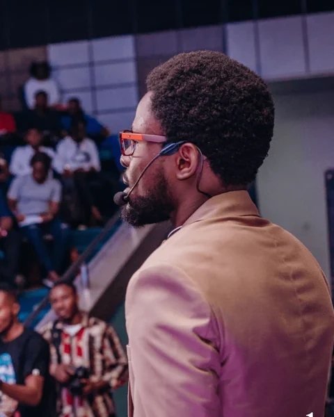 Ayodeji on stage, speaking to a full auditorium at DSGN Discussions