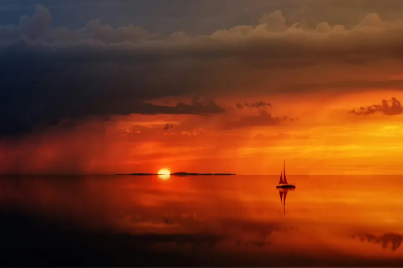A lone sailboat on still water beneath a storm cloud at sunset